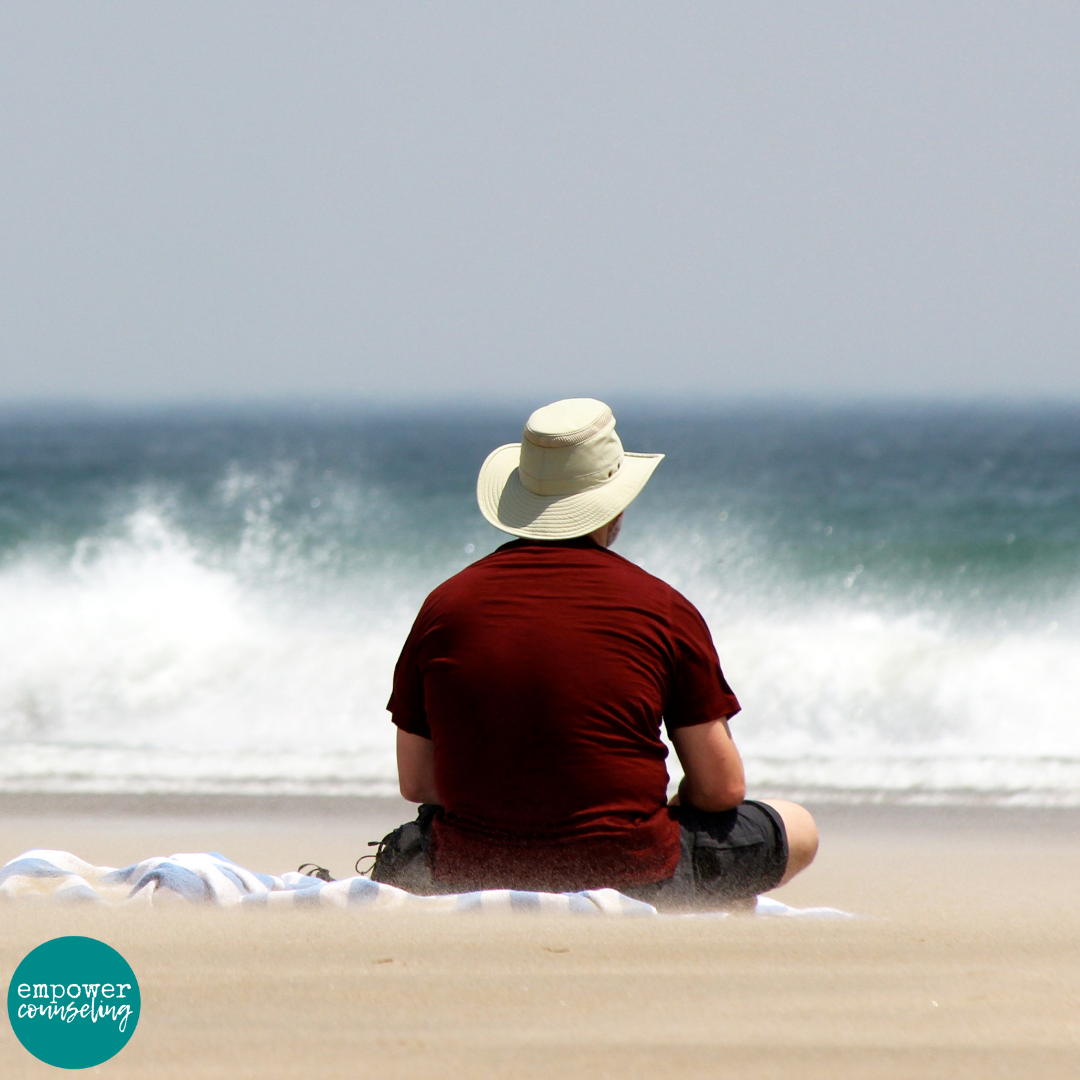 A man sits on the beach, wondering how to handle tough times as he gazes at angry waves crashing onto the shore. The stormy ocean reflects the emotional turbulence of facing life’s challenges. This image accompanies the blog post "Staying Safe When the Waves Get Rough: How to Handle Tough Times," written from the perspective of a trauma therapist in Atlanta, offering strategies to navigate difficult moments with resilience and confidence.